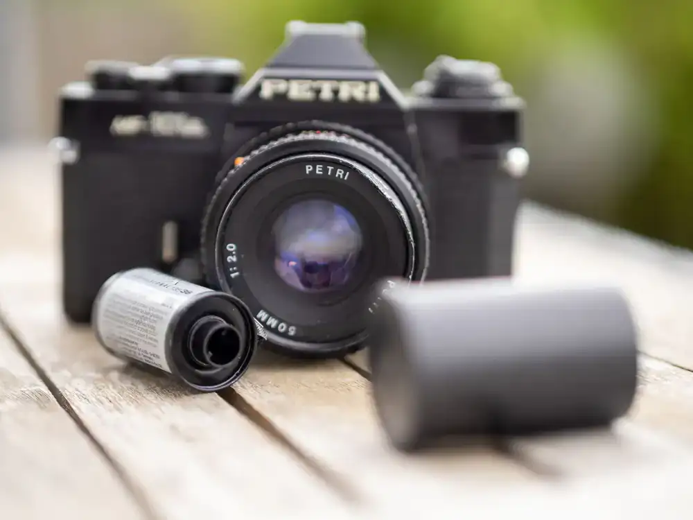 Classic 35mm SLR camera resting on a wooden table